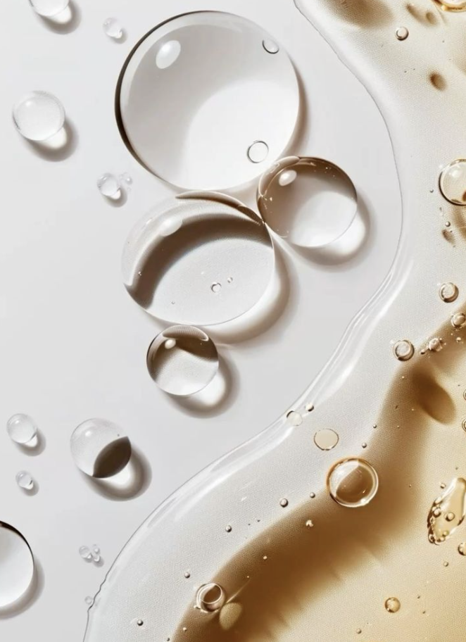 Macro photograph of clear serum gel bubbles and golden oil droplets on a soft neutral background